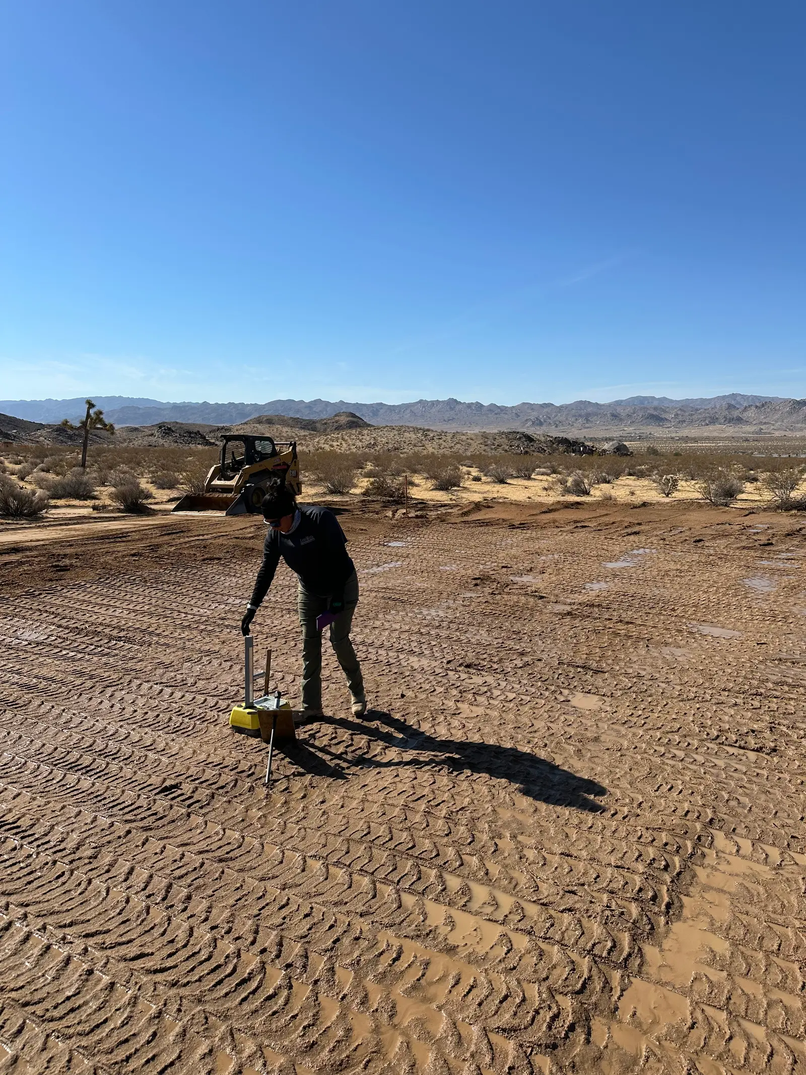 Wide view of the graded pad and surrounding desert with compaction equipment still on site.